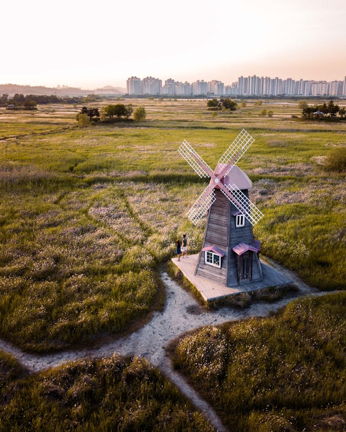 Aerial shot of a charming windmill set in a vast countryside landscape at sunset.