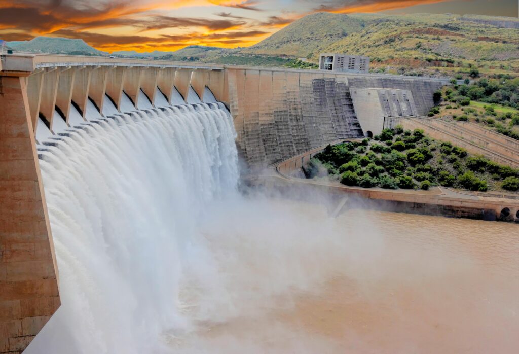 Scenic view of a large dam with cascading water and dramatic sunset skies.